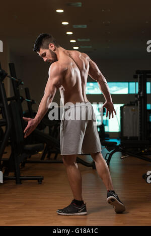 Jeune homme debout forte dans la salle de sport et Flexing Muscles musculaire - Fitness Model Posing Bodybuilder athlétiques exercices après Banque D'Images