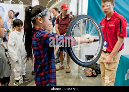 La physique d'apprentissage jeune fille de gyroscope avec une roue de vélo à une expo-sciences - USA Banque D'Images