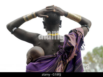 Femme de la tribu Mursi portant son bébé dans son dos, la vallée de l'Omo, Ethiopie, parc de Mago Banque D'Images