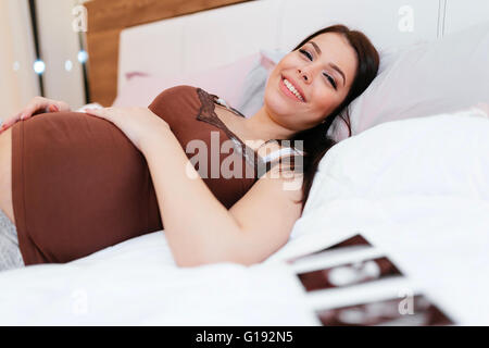 Belle femme enceinte et scan on bed Banque D'Images
