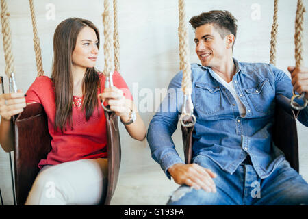 Young couple relaxing in swing tout en parlant et le flirt Banque D'Images