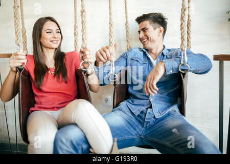 Young couple relaxing in swing tout en parlant et le flirt Banque D'Images