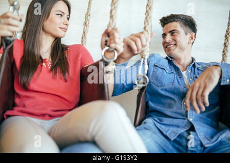 Young couple relaxing in swing tout en parlant et le flirt Banque D'Images