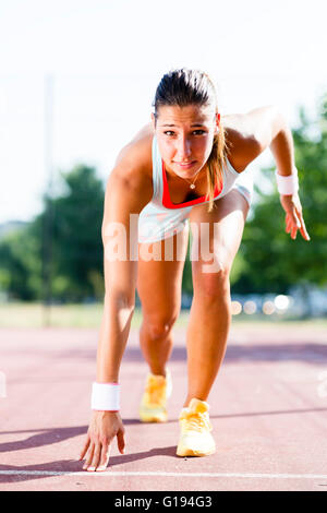 Belle femme sprinter se préparer pour l'exécuter au cours de l'été Banque D'Images