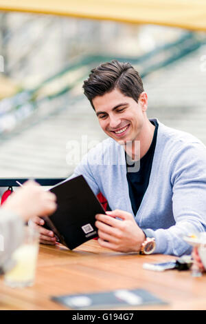 Beau jeune homme à la recherche, à l'aide du menu à l'extérieur Banque D'Images