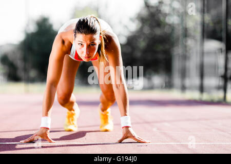 Belle femme sprinter se préparer pour l'exécuter au cours de l'été Banque D'Images