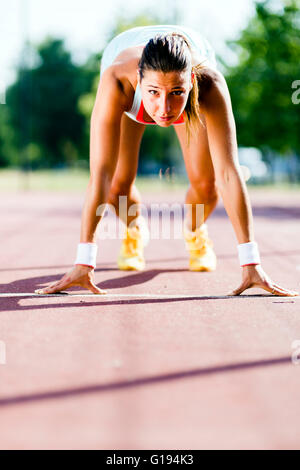 Belle femme sprinter se préparer pour l'exécuter au cours de l'été Banque D'Images