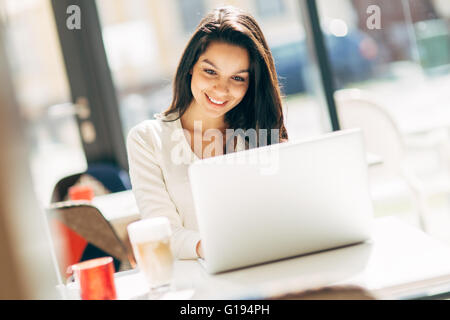 Belle brunette using laptop in cafe Banque D'Images