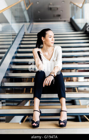 Businesswoman sitting on stairs et la pensée. Photo fashion style Banque D'Images