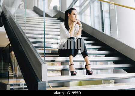 Businesswoman sitting on stairs et la pensée. Photo fashion style Banque D'Images