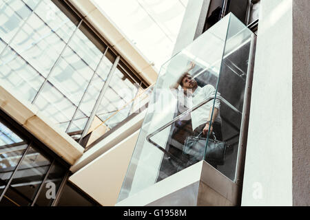 Businessman taking ascenseur en verre moderne à l''étage supérieur Banque D'Images