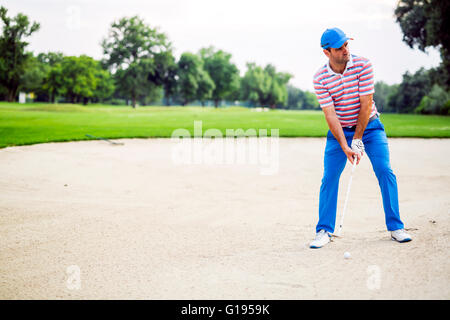 Prendre un golfeur bunker avec le ballon dans le sable Banque D'Images