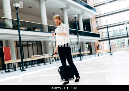 Beau business holding un chariot et la marche à pied dans un bâtiment moderne Banque D'Images
