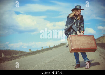 Fille avec une valise sur la route Banque D'Images