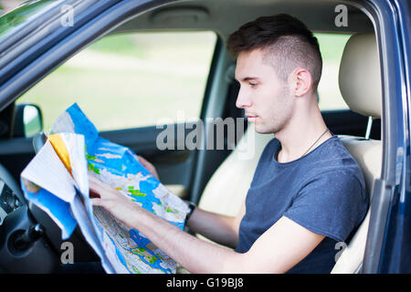 Photo d'un voyageur stationné sa voiture par le côté d'une route, perdu et la lecture de la carte. Se concentrer sur la carte et de sexe masculin. Banque D'Images