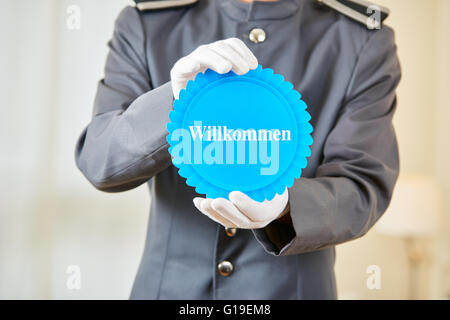 Commis d'hôtel holding badge allemand dire "Willkommen" (Bienvenue) dans une chambre d'hôtel Banque D'Images