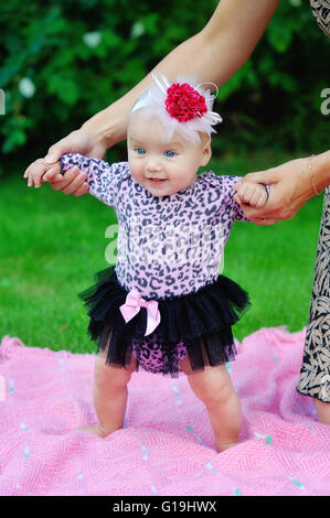 Beautiful happy little baby girl sitting on un pré vert avec Banque D'Images