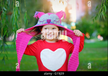 Beau rire petit bébé fille dans un manteau rouge et colorfu Banque D'Images