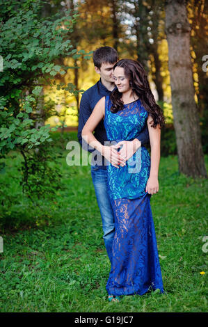 Smiling young couple in love de l'emplacement sur un banc dans le parc Banque D'Images