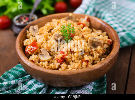 Le boulgour avec le poulet, les champignons et les tomates dans un bol en bois. Vue d'en haut Banque D'Images