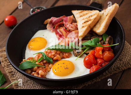 Petit-déjeuner anglais - œuf frit, haricots, tomates, champignons, bacon et pain grillé Banque D'Images