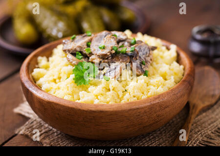 Porridge de millet aux champignons dans un bol en bois Banque D'Images