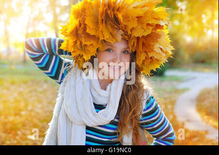 Jolie jeune femme à l'automne parc est une couronne de feuilles Banque D'Images