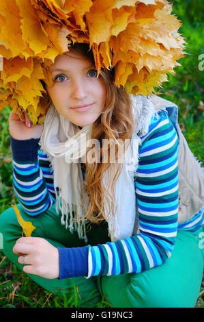 Jolie jeune femme à l'automne parc est une couronne de feuilles Banque D'Images