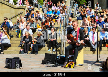 Jeune homme de la rue dans la région de Buchanan Street, Glasgow avec un inproptu public assis sur les marches derrière pendant l'été Banque D'Images