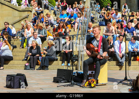 Jeune homme de la rue dans la région de Buchanan Street, Glasgow avec un public assis sur les marches derrière pendant l'été Banque D'Images