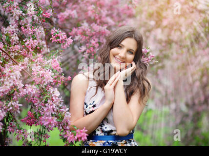 Belle fille de jardin de printemps parmi les arbres en fleurs avec pink Banque D'Images