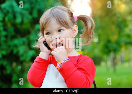 Petite fille de crier dans le téléphone dans un parc Banque D'Images