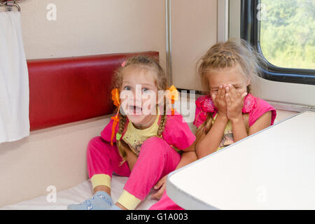 Deux petites filles gaies sont assis dans le train pour abaisser le second-class place voiture dans le même pyjama. Banque D'Images