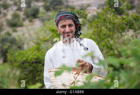 Les hommes en costume traditionnel omanais montrant outre de panier plein de pétales de rose Banque D'Images