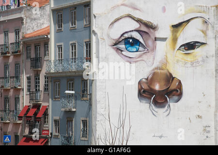 Une grande fresque surréaliste d'un visage peint sur le pignon d'une rangée d'immeubles à appartements de São Bento, Lisbonne, Portugal. Banque D'Images