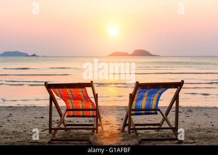 Deux chaises longues sur la plage au coucher du soleil. Banque D'Images