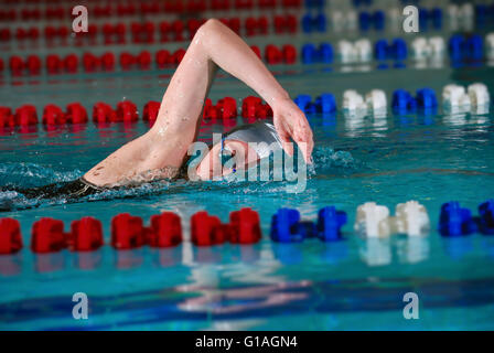 Femme à l'aide de la course de nage crawl dans une piscine intérieure Banque D'Images