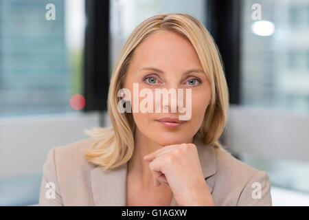 Portrait of businesswoman in modern office. La construction en arrière-plan. Looking at camera Banque D'Images