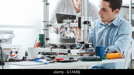 Les étudiants en ingénierie à l'aide d'une imprimante 3D dans le laboratoire Banque D'Images