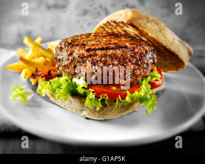 Burger de boeuf ou un hamburger dans un petit pain avec aliments complets avec des frites Banque D'Images