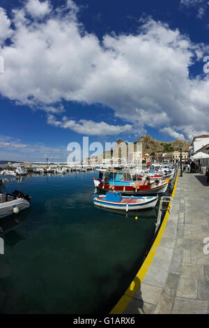 Myrina city waterfront spectaculaires sous temps nuageux, bateaux & réflexions dans l'avant-plan et ancien château loin. Lemnos Grèce Banque D'Images