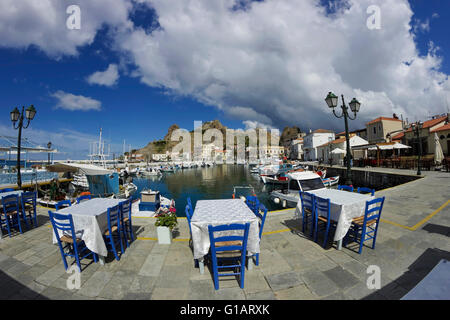 'Happy Days' restaurant tables avec sièges bleu, vue sur le château et la ville spectaculaire quay & temps nuageux. Limnos, Grèce Banque D'Images
