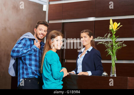 Jeune couple avec réceptionniste pendant l'inscription à l'hôtel à l'accueil Banque D'Images