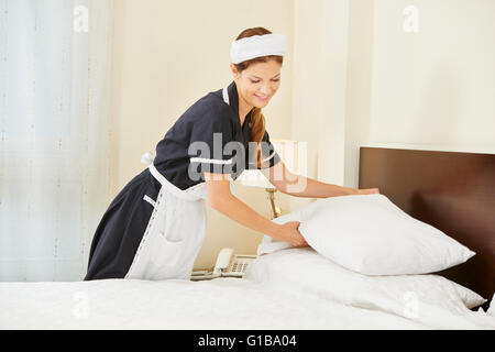 Hotel maid making bed dans la chambre d'hôtel pendant le ménage Banque D'Images