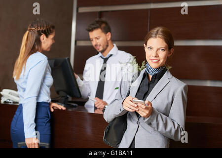 Woman with smartphone à l'arrivée dans un hôtel Banque D'Images