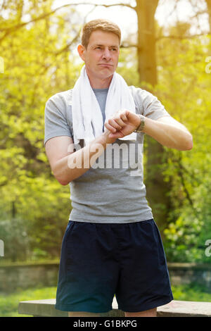 Dans sportsgear man standing outdoors regardant sa montre Banque D'Images
