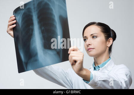 Confident female doctor examining précisément une cage thoracique x-ray. Banque D'Images