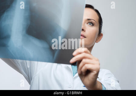 Confident female doctor examining précisément une cage thoracique x-ray. Banque D'Images