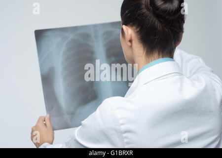 Confident female doctor examining précisément une cage thoracique x-ray. Banque D'Images