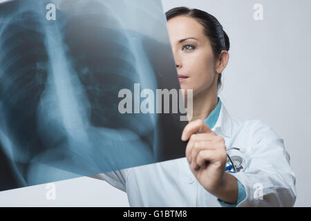 Confident female doctor examining précisément une cage thoracique x-ray. Banque D'Images